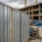Rij van hoge gegalvaniseerde stalen bouwplaatshekken op een Europese stedelijke bouwplaats, met betonnen barriers en een gebouw in aanbouw op de achtergrond.