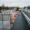 Wegwerkzaamheden op Europese snelweg met A-frames, stalen barriers, oranje verkeerskegels en een verzinkte stalen bordhouder op de voorgrond.