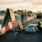Verkeersbordenrekken en A-frames in Europese wegenbouwzone, arbeider in fluohesje inspecteert verzinkt stalen signalisatiemateriaal.