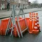 Oranje-rode verkeersbarriers en A-borden op grijs asfalt in een Nederlandse stad, met reflecterende delineatoren en verkeerskegels.